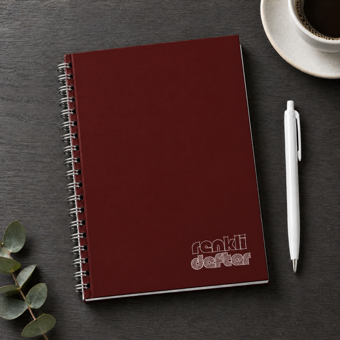 Bordo defter A5 yandan spiralli sert kapak, beyaz kalem hediyeli, antrasit masa üzerinde