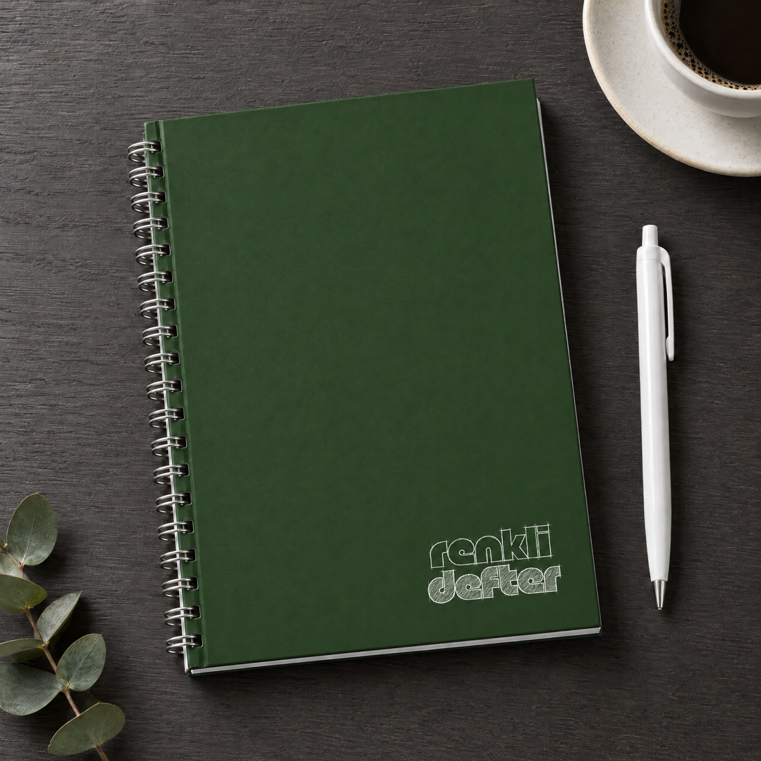 Yeşil defter A5 yandan spiralli sert kapak, beyaz kalem hediyeli, antrasit masa üzerinde